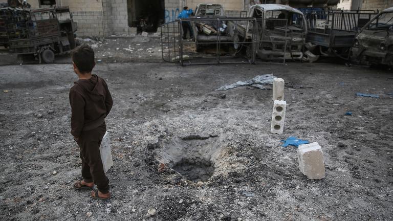 Archiv: Ein syrisches Kind geht an einem Loch im Boden vorbei, das sich nach einem Raketenbeschuss gebildet hat, aufgenommen am 03.03.2020 in Idlib, Syrien