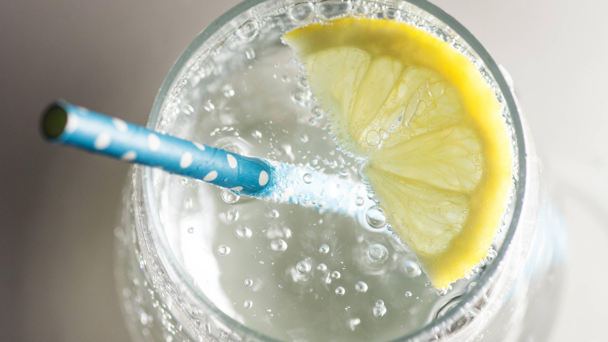 Wasser in einem Glas mit Strohhalm und einer Zitronenscheibe