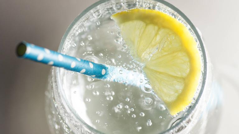 Wasser in einem Glas mit Strohhalm und einer Zitronenscheibe