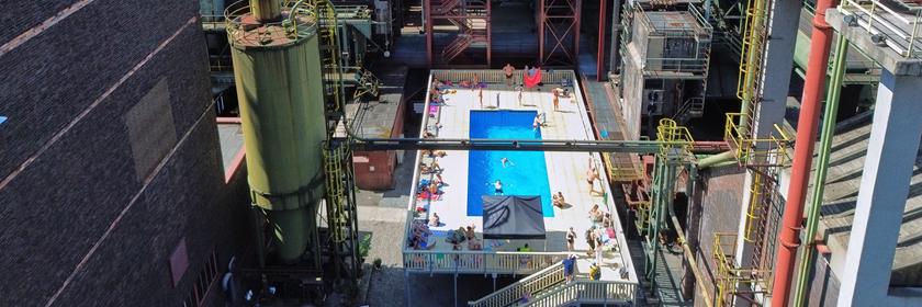 Ein Pool zwischen großen alten Industriegebäuden.