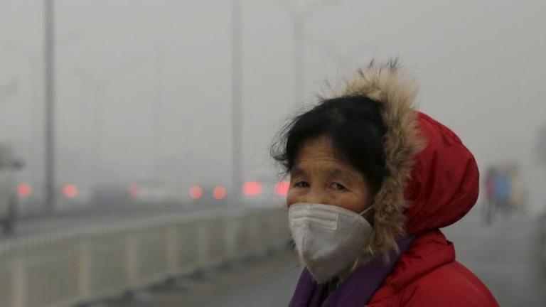Zum Schutz vor Smog in Peking trägt die Frau eine Schutzmaske.