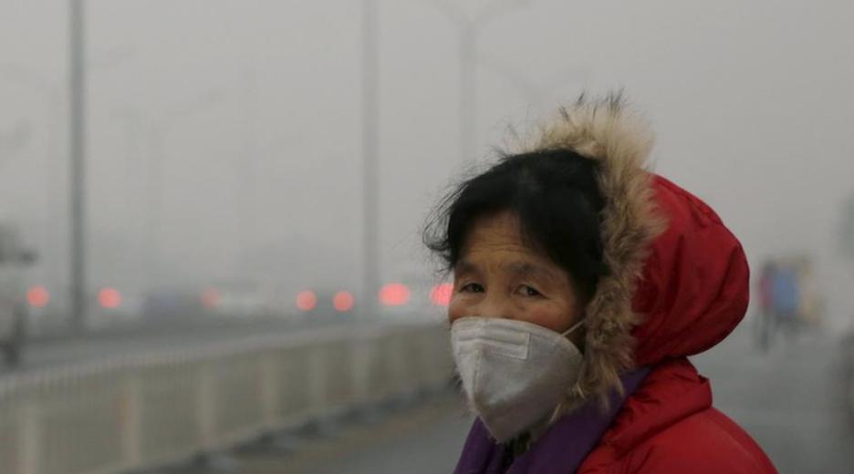 Zum Schutz vor Smog in Peking trägt die Frau eine Schutzmaske.